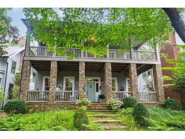 Two-story home with stone columns, large porch, and lush landscaping at 9032 Selborne Ln, Chattahoochee Hills, GA 30268