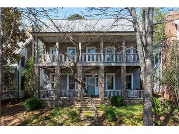 Charming two-story home features a stone foundation and a welcoming covered front porch and second story balcony at 9032 Selborne Ln, Chattahoochee Hills, GA 30268