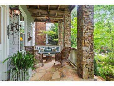 Inviting front porch with stone columns, wicker furniture, and a stone floor at 9032 Selborne Ln, Chattahoochee Hills, GA 30268