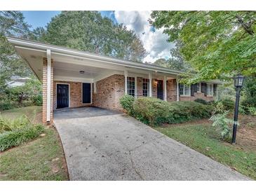 Brick ranch house with carport, landscaping, and a long driveway at 3839 Redbud Se Ct, Smyrna, GA 30082