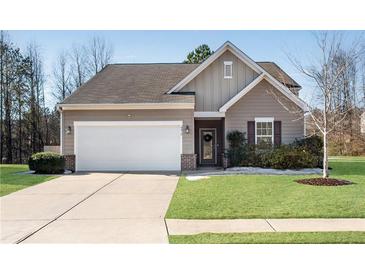 Tan house with white garage door, landscaping, and a brick accent at 4410 Chaney Ct, Cumming, GA 30028