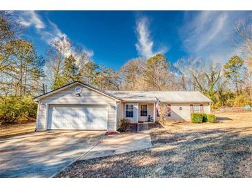 House exterior featuring a beige vinyl siding, attached garage, and manicured lawn at 12524 Highway 36, Covington, GA 30014