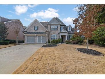 Brick two-story home with three-car garage and manicured lawn at 104 Johnston Farm Ln, Woodstock, GA 30188