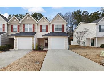 Tan siding townhouse with red shutters, two-car garage, and landscaping at 6977 Gallant Se Cir # 8, Mableton, GA 30126