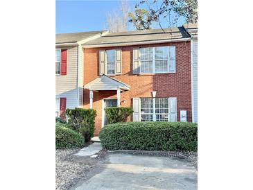 Brick two-story townhome with gray door, shutters, and manicured landscaping at 2884 Norfair Loop, Lithonia, GA 30038
