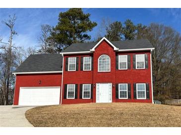 Two-story red brick house with a white door, black shutters, and a two-car garage at 1029 Chaterly Ct, Riverdale, GA 30296