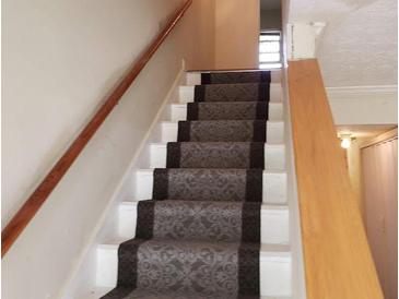 Carpeted staircase with wooden handrails leads to the upper level of this home at 345 Lexington Dr, Lawrenceville, GA 30046