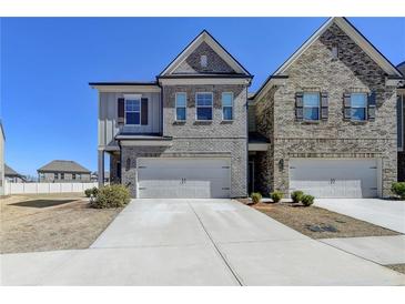 Charming townhome with a two-car garage, neutral brick, and manicured landscaping at 3353 Pearl Ridge Way, Buford, GA 30519