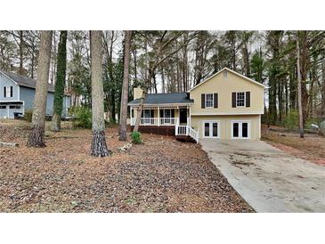 Updated yellow house with a covered porch and driveway, nestled among tall trees at 368 Sumer Ln, Douglasville, GA 30134