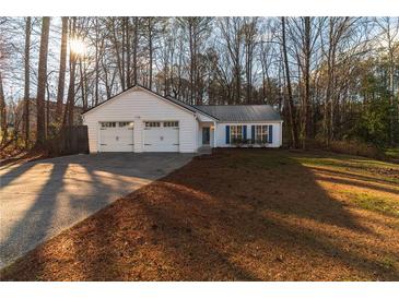 White house with two-car garage and a yard at 415 Rockingham Ln, Woodstock, GA 30189