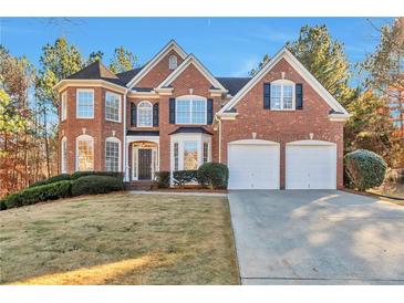 Brick two-story house with a three-car garage and manicured lawn at 5506 Sara Creek Ln, Sugar Hill, GA 30518