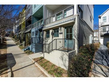 Charming townhouse with brick facade, blue door, black railings, and a small front yard at 711 Needletail Way, Atlanta, GA 30312