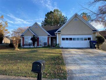 Tan two-story house with a white garage door and landscaped lawn at 2800 Camelot Woods Dr, Lawrenceville, GA 30044