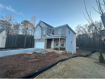 Two-story house with gray siding and brick accents, attached garage, and covered porch at 566 Abbott Se Ct, Atlanta, GA 30354