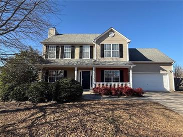 Two-story house with a beige exterior, black shutters, and a red brick accent at 1563 Nicole Ridge Ct, Loganville, GA 30052