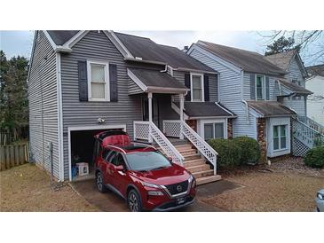 Two-story townhome with gray siding, attached garage, and a red SUV parked in the driveway at 390 Lakeridge Ct, Riverdale, GA 30274