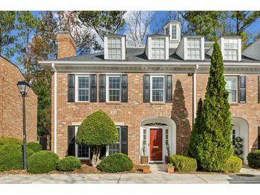 Brick townhouse with a red door, landscaping, and dormer windows at 15 Independence Nw Pl, Atlanta, GA 30318