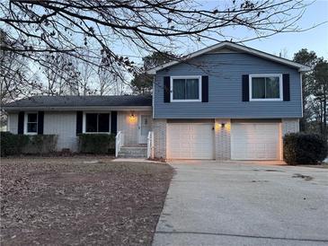 Two-story house with brick and blue siding, two-car garage, and a landscaped yard at 2778 Majestic Cir, Dacula, GA 30019