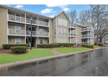 Condominium complex featuring multiple floors and private balconies, surrounded by green landscaping and mature trees at 411 Berkeley Woods Dr, Duluth, GA 30096