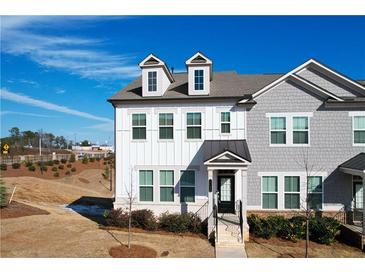 Two-story townhome with gray and white siding, a front porch, and landscaping at 2709 Richmond Row Dr, Suwanee, GA 30024