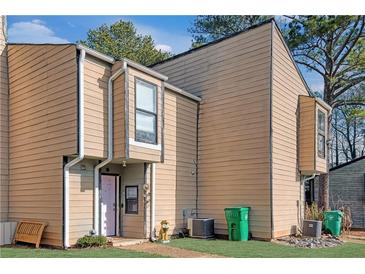 Tan colored siding townhouse with green trash cans and small front yard at 6034 Regent Mnr, Lithonia, GA 30058