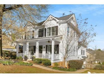 Charming two-story white home featuring a welcoming front porch, black shutters and professionally landscaped yard at 1399 Knob Hill Se Ct, Atlanta, GA 30316