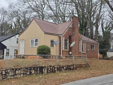 Brick and tan house with metal roof, satellite dish, and fenced yard at 1643 Westhaven Sw Dr, Atlanta, GA 30311