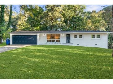 Newly renovated ranch home with a white brick exterior, dark garage door, and a well-manicured lawn at 1921 Westwood Sw Ave, Atlanta, GA 30310