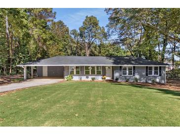 Newly renovated ranch home with gray siding, spacious lawn, and long driveway at 1352 Jennie Sw Ln, Lilburn, GA 30047
