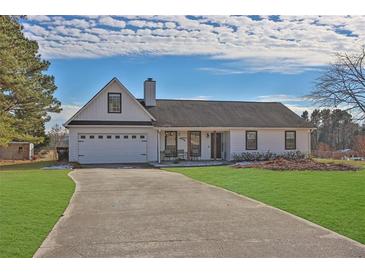 White house with a two-car garage and a large yard at 6460 Dove Dr, Loganville, GA 30052