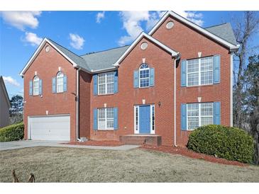 Brick house with blue door and shutters, two-car garage, and landscaped lawn at 4414 Parmalee Path, Conley, GA 30288
