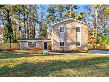 Brick house with a well-maintained lawn and wooden fence at 5533 N Wind Sw Dr, Lilburn, GA 30047