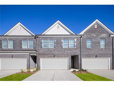 Three-unit townhome building with gray brick exterior, attached garages, and small front yards at 237 Epping St # 89, Stockbridge, GA 30281