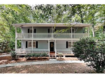 Charming home featuring a classic two-story design with dual-level balconies and a surrounding wooded landscape at 3337 Devaughn Ne Dr, Marietta, GA 30066