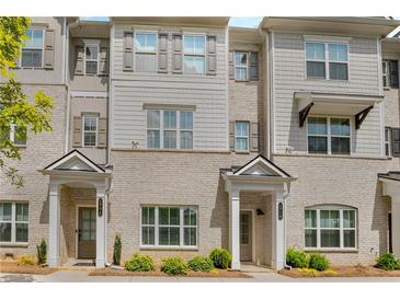 Beige brick townhome with gray shutters, white columns, and landscaping at 1708 Evenstad Way, Smyrna, GA 30080