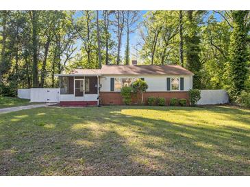 Charming single-story home with a brick foundation, screened porch, and a lush green lawn surrounded by mature trees at 1931 Oana Sw St, Atlanta, GA 30310