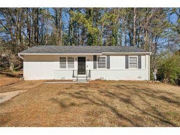 White ranch house with gray roof and black door, surrounded by trees at 3563 Bolfair Nw Dr, Atlanta, GA 30331