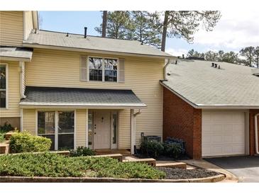 Charming townhouse featuring yellow siding, a brick facade and an attached single car garage at 6806 Glenridge Dr # E, Atlanta, GA 30328