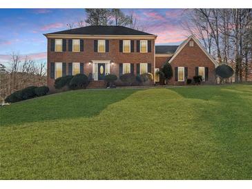 Charming two-story brick home with lush front lawn and mature trees on an overcast day at 5659 Brookstone Nw Dr, Acworth, GA 30101