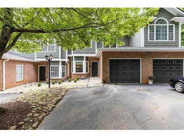 Brick and gray-sided townhouse with 2-car garage, landscaping, and a spacious driveway at 2680 Pine Tree Ne Rd # 2, Atlanta, GA 30324