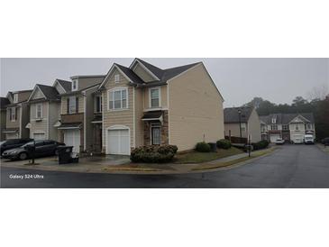 Tan three-story townhome with white garage door, located in a quiet neighborhood at 1944 Dilcrest Dr, Duluth, GA 30096