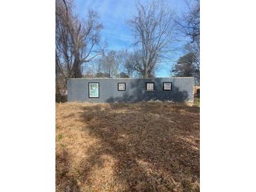 Grey block building with four small windows, situated on a lot with leaf-covered ground at 2025 Moody Sw Dr, Atlanta, GA 30315