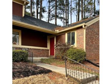 Charming townhome with a red door, brick accents, and lush landscaping at 49 Country Ct, Alpharetta, GA 30005