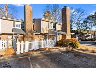 Two-story townhome with brick and siding exterior, white picket fence, and ample parking at 557 Summit Sw Ln, Marietta, GA 30008