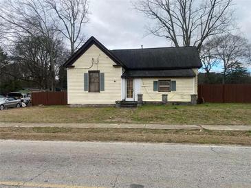 Full view of a fixer-upper house needing renovation, with a fenced yard at 7163 Swift St, Lithonia, GA 30058