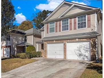 Tan two-story house with a two-car garage and manicured lawn at 1835 Roble Dr, Atlanta, GA 30349