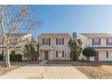 Two-story townhome with tan siding, brown door, and small front yard at 320 Goldenrod Dr, Stockbridge, GA 30281