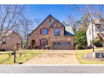 Charming stone home featuring a well-manicured lawn and two-car garage at 4595 Carriage Walk Ln, Cumming, GA 30040