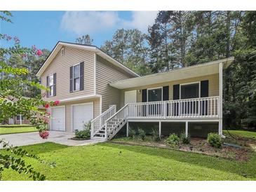 Tan house with a double garage and front porch at 3980 Carlton Cove Ct, Loganville, GA 30052