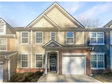 Two-story townhome with neutral siding, brick accents, and a two-car garage at 4154 Magnolia Glen Walk, Norcross, GA 30093